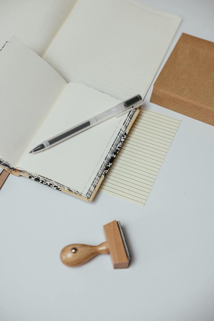 Open notebook, stamp, ballpoint pen on a white desk